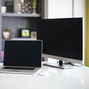 This is an image of a laptop and a desktop pc (personal computer) on a white desk